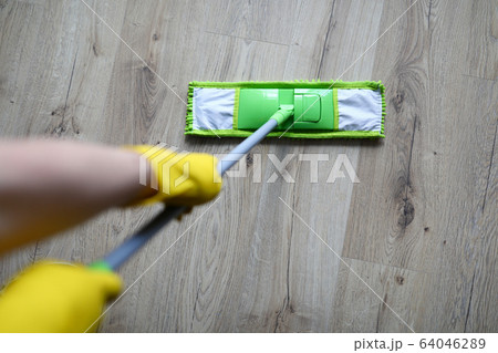 Male hand with yellow protective gloves hold green plastic mop Male hand with yellow protective gloves hold green plastic mop 64046289