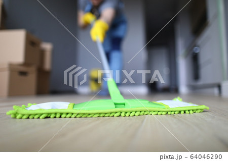 Male hand with yellow protective gloves hold green plastic mop Male hand with yellow protective gloves hold green plastic mop 64046290