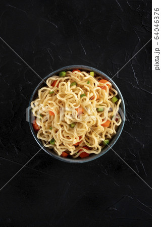 Instant noodles bowl with carrot and scallions, top-down shot on a black background with a place for text 64046376