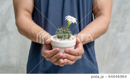The man holds a pot to plant a cactus. The man holds a pot to plant a cactus. 64046964