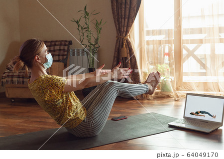 Sporty young woman taking yoga lessons online and practice at home while being quarantine 64049170