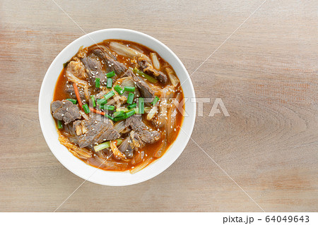 top view of stir fried beef with kimchi in a ceramic bowl on wooden table. top view of stir fried beef with kimchi in a ceramic bowl on wooden table. 64049643