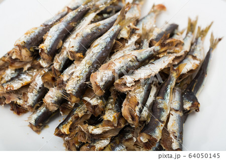 Deliciously cooked baked sprats served on white plate at table Deliciously cooked baked sprats served on white plate at table 64050145