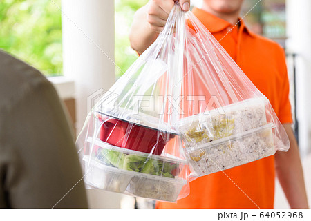 Delivery man giving lunch box meal to customer Delivery man giving lunch box meal to customer 64052968