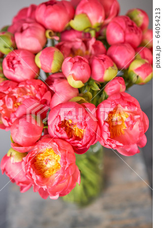 Coral peonies in a glass vase on wooden table. Beautiful peony flower for catalog or online store. Floral shop concept . Beautiful fresh cut bouquet. Flowers delivery. Coral peonies in a glass vase on wooden table. Beautiful peony flower for catalog or online store. Floral shop concept . Beautiful fresh cut bouquet. Flowers delivery. 64054213