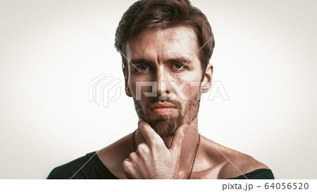 Serious Macho Touching His Chin While Looking At Camera 64056520