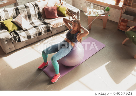 Young woman teaching at home online courses of fitness, aerobic, sporty lifestyle while being quarantine 64057923