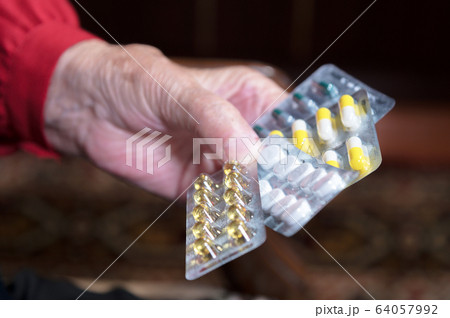 Closeup hands of an old woman hold many different pills in hands. The concept of drug selection and the health of the older generation 64057992