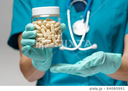 medical doctor nurse woman wearing protective mask and rubber or latex gloves - holding pills medical doctor nurse woman wearing protective mask and rubber or latex gloves - holding pills 64060991
