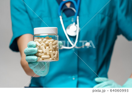 medical doctor nurse woman wearing protective mask and rubber or latex gloves - holding pills medical doctor nurse woman wearing protective mask and rubber or latex gloves - holding pills 64060993