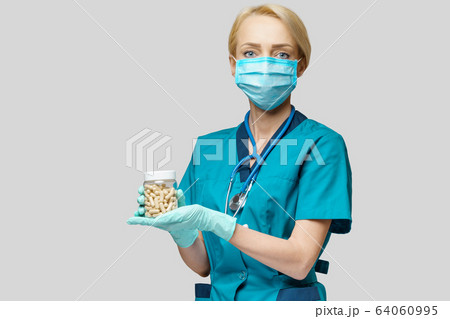 medical doctor nurse woman wearing protective mask and rubber or latex gloves - holding pills medical doctor nurse woman wearing protective mask and rubber or latex gloves - holding pills 64060995