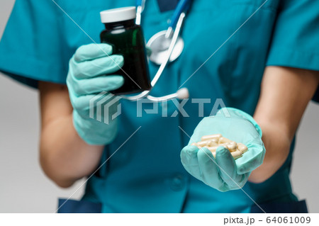 medical doctor nurse woman wearing protective mask and rubber or latex gloves - holding pills medical doctor nurse woman wearing protective mask and rubber or latex gloves - holding pills 64061009