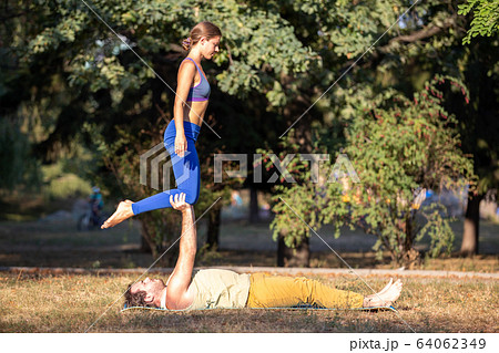 Young couple doing acroyoga exercises in park Young couple doing acroyoga exercises in park 64062349