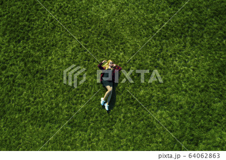 Happy woman relaxing on the grass. Aerial top view of vacation during sunny summer day 64062863