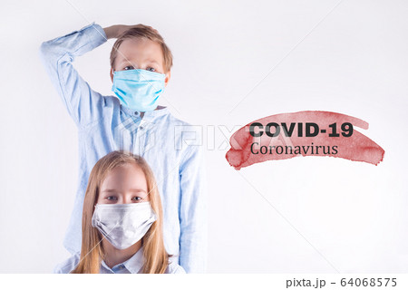 Two kids boy standing behind girl in medical protective masks against light grey background. Two kids boy standing behind girl in medical protective masks against light grey background. 64068575