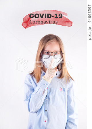 Pretty young girl in a medical protective mask is making a quiet gesture against light grey background. Pretty young girl in a medical protective mask is making a quiet gesture against light grey background. 64068597