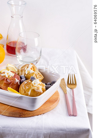 Baked apples with blueberries and cottage cheese in bowl with cutlery on white table Baked apples with blueberries and cottage cheese in bowl with cutlery on white table 64069576