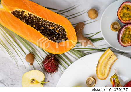 Exotic fruits and tropical leaves on table Exotic fruits and tropical leaves on table 64070177