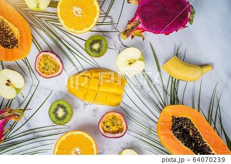 Exotic fruits and tropical leaves on table 64070239