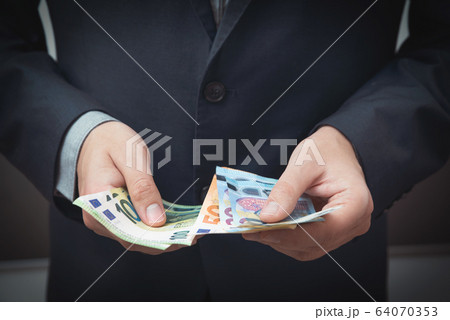 Man in a suit counts Euro banknotes 64070353