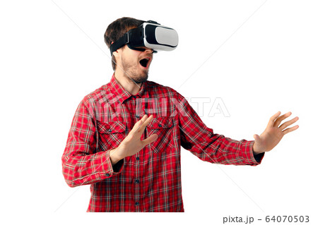 Man emotional playing, using virtual reality headset isolated on white studio background Man emotional playing, using virtual reality headset isolated on white studio background 64070503