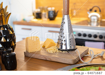 A piece of cheese on a wooden board next to an 64071687