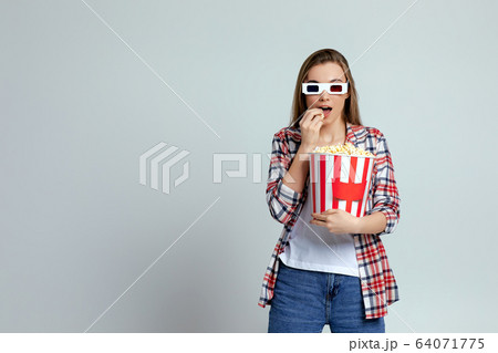 beautiful young woman eating popcorn from bucket 64071775