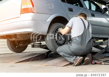 Car wheel repair shop outdoor ground . Seasonal winter tyre change at workshop. Vehicle tire repair, inspection and maintenance. Automotive garage for replace spare parts after failure breakdown 64072397