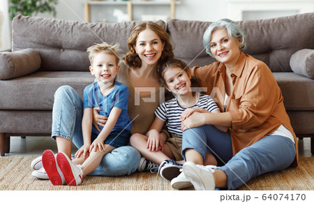 Several generations sitting on floor near sofa. 64074170