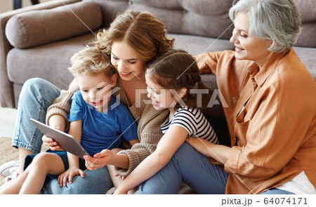 Women and kids browsing tablet on floor together. Women and kids browsing tablet on floor together. 64074171
