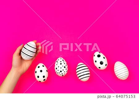 Different graphic hand-painted eggs on bright pink background. 64075153
