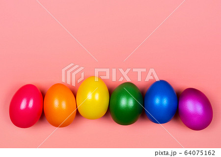 Different colorful eggs in neon trendy colors on coral background. 64075162