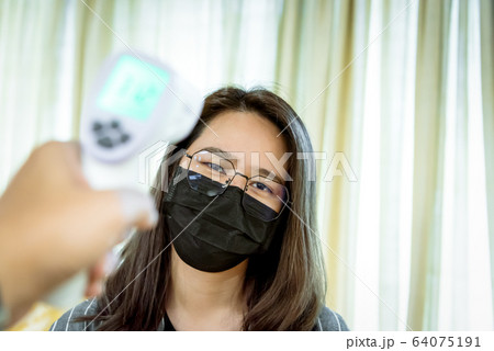 Woman wearing mask protection flu with thermoscan 64075191