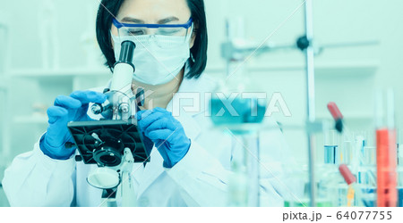 Scientis using microscope to work in lab. 64077755