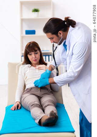 Injured young woman visiting young male doctor 64077908