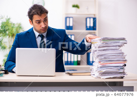 Young male employee unhappy with excessive work 64077976