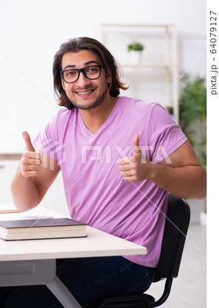 Young male student preparing for exams at classroom Young male student preparing for exams at classroom 64079127