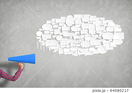 Hand of woman holding blue paper trumpet against concrete background 64080217