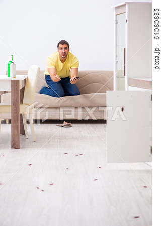 Young man and a lot of cockroaches at home 64080835