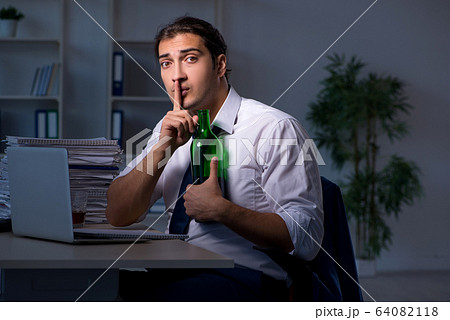 Alcohol addicted businessman working late in the office Alcohol addicted businessman working late in the office 64082118