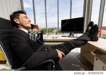 Businessman sits and talking to smartphone.. 64083076