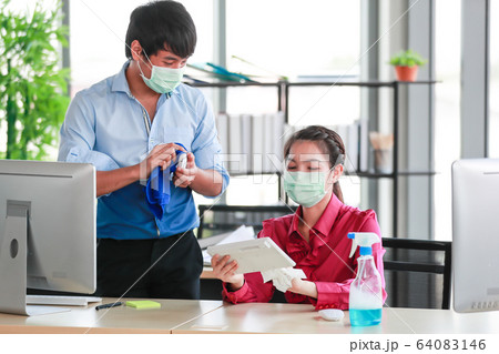 Employee disinfecting office equipment. Employee disinfecting office equipment. 64083146