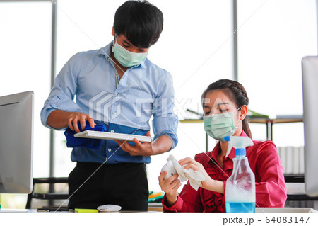 Employee disinfecting office equipment. 64083147
