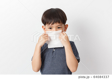 Little asian boy holding a tissue and blow his 64084337
