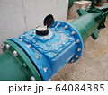 Closeup - of the blue industrial water meter With green metal pipes for supplying water and many fasteners On a cement floor background. Selective focus 64084385