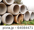 Old concrete drains that are clogged with new outdoor pipes. Industrial concrete pipes are laid on the ground beside the construction road. Selective focus 64084471