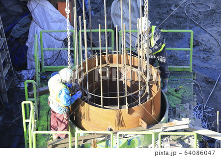建築現場　基礎工事　ガイドパイプと鉄筋連結作業 64086047