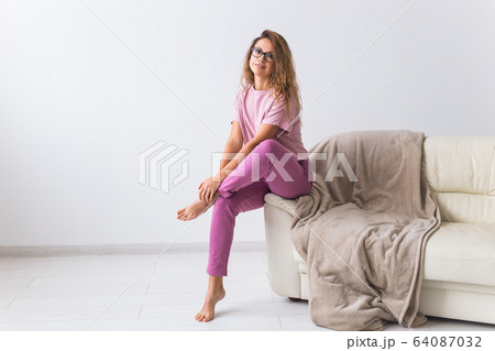 Young attractive woman dressed in beautiful colorful pajama posing as a model in her living room. Comfortable sleepwear, home relaxation and female fashion concept. 64087032