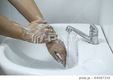 Woman washing hands under the water tap in 64087350