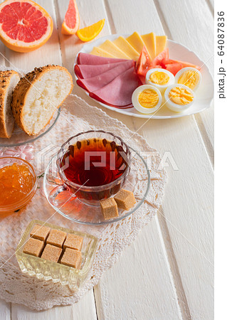 Fresh delicious breakfast with soft boiled egg, cheese, ham fresh bread and cup coffee or tea on light wooden background. 64087836